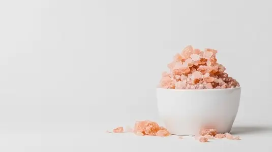 Small bowl of pink Himalayan salt with scattered crystals