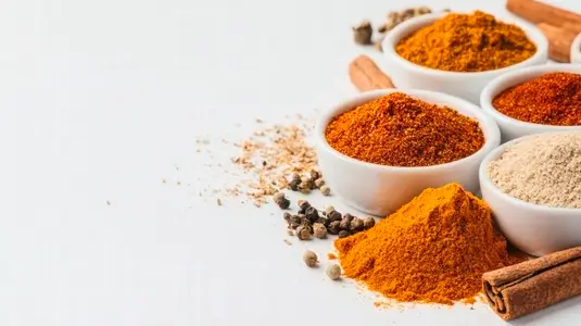Various colorful spices in small piles on white background
