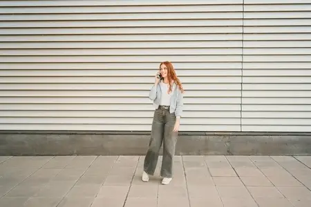 A casual young woman  dressed in a trendy and stylish outfit  is engaging in a phone conversation