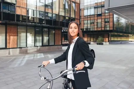 Portrait of a young woman in formal wear looking at camera and holding bicycle handlebars  Businesswoman during her ride to the office