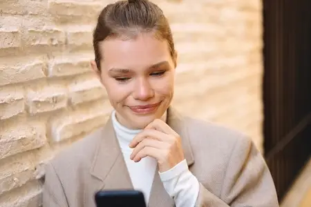 A young woman is engaged and absorbed with her smartphone while situated in a cozy urban setting