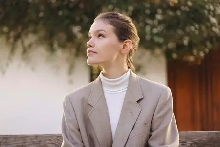 Contemplative Woman in a Stylish Blazer Enjoying Time Outdoors Surrounded by Nature and Greenery