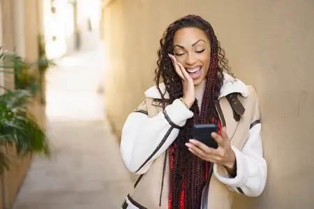 An Excited Woman Reacting Enthusiastically to Good News Over the Phone in Daylight