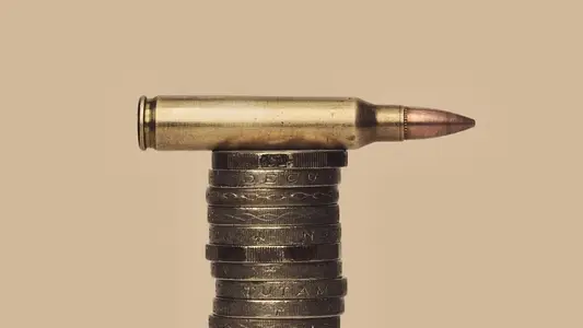 UK Defense Spending still life of bullet cartridge on stack of British Pound coins
