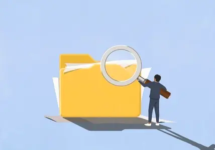 Businessman holding large magnifying glass over large messy file folder