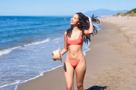A Joyful Woman Fully Enjoying a Wonderful Day at the Beach with Her Refreshing Coconut Drink