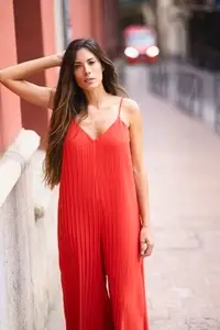 A Stylish Woman Dressed in a Bold Red Jumpsuit Posing Confidently on an Urban Street Scene