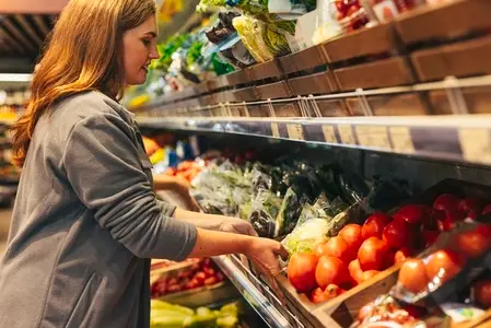 Female grocery store worker refreshing products on the shelf  moving a box