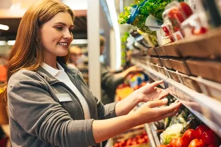 Smiling female worker of a grocery store adjusting the food counter