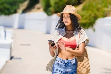 A Stylish Woman in a Chic Summer Outfit is Enjoying a Relaxing Day Outdoors with Her Smartphone