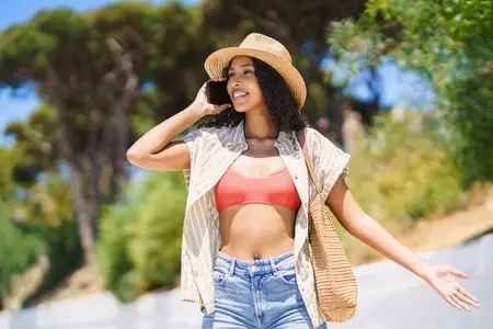 A young woman joyfully enjoys a summer day in a casual outfit and stylish straw hat