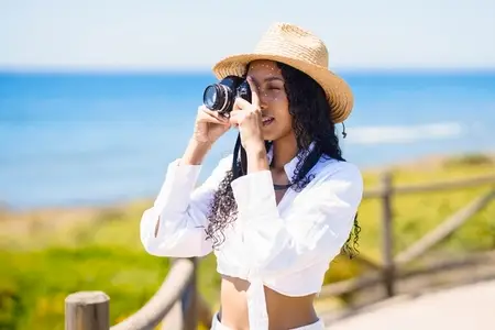 A Young Woman Joyfully Capturing Beautiful Summer Moments at the Picturesque Beach