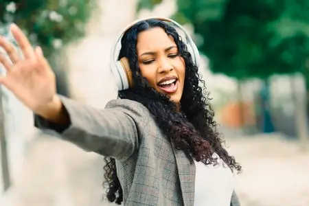 A Joyful Woman Dancing Freely with Headphones on in a Lively Urban Setting Filled with Energy