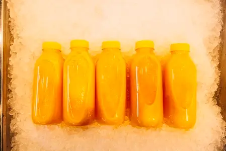 Five bottles with orange juice on the ice  shot from above