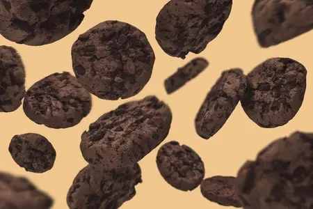 Chocolate chip cookies falling against yellow background