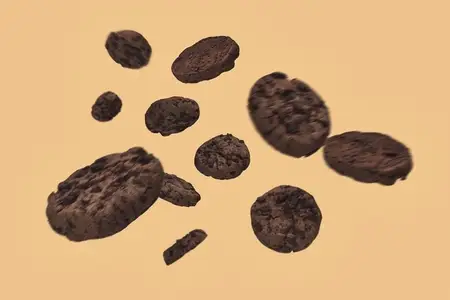 Blurred chocolate chip cookies falling against beige background
