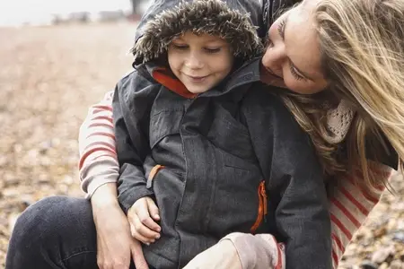 Happy mother and son in warm jacket on winter beach