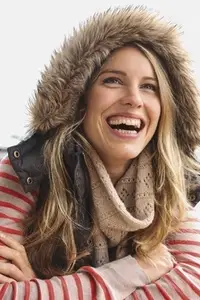 Portrait of happy carefree woman in fur lined hood laughing with mouth open