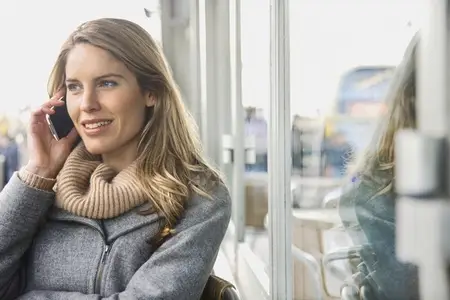 Smiling blond woman talking on smart phone at sidewalk cafe Smiling blond woman talking on smart phone at sidewalk cafe