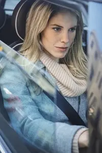 View of beautiful blond woman in scarf driving car from window