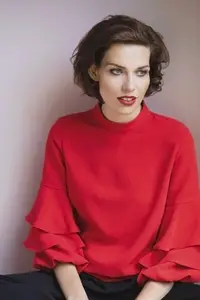 Studio portrait of beautiful young brunette woman in red blouse with ruffled sleeves looking away