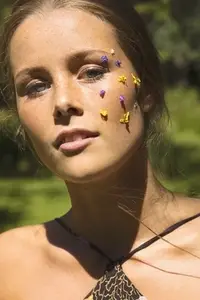 Close up portrait of beautiful young woman with purple and yellow flower petals on face