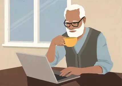 Senior man with beard drinking coffee and using laptop at home