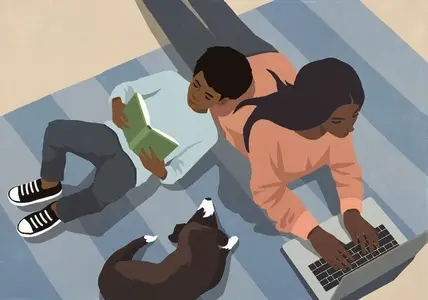 High angle view of boy reading book laying on mother working at laptop by dog on rug at home