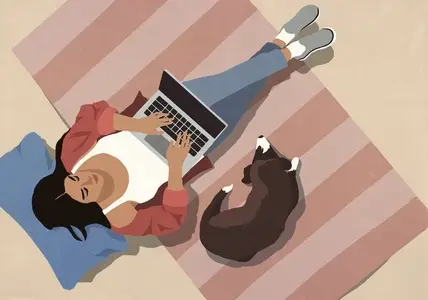 View from above of dog laying on rug next to woman using laptop at home