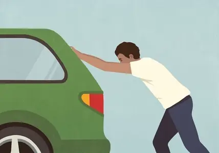 Man pushing broken down green car against blue background