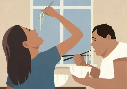 Couple eating pho noodles from bowls with fork and chopsticks at home