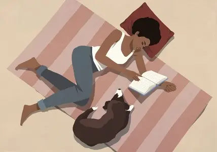 View from above of woman relaxing at home reading book on floor next to dog