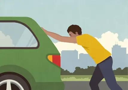 Man pushing broken down green car on city road