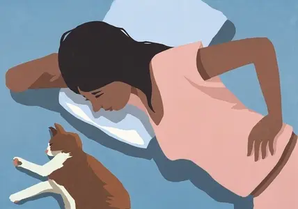 View from above of woman laying in bed watching cat sleeping