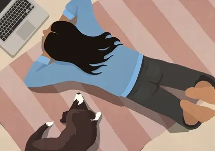 View from above of dog laying next to woman using laptop on striped rug on floor at home