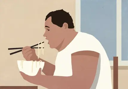 Overweight man eating noodles from bowl with chopsticks by window at home