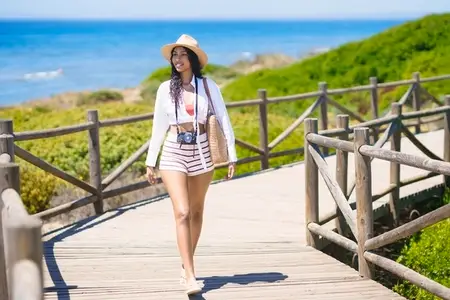 A Woman Happily Enjoying a Leisurely Walk Along the Beach on a Beautiful Sunny Day
