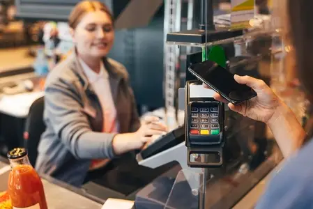 Unrecognizable woman paying by phone at the counter in a grocery store