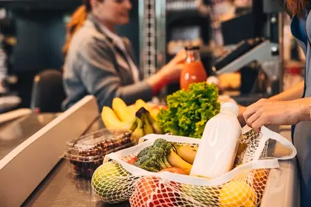 Close up of a string bag full of groceries at counter in store