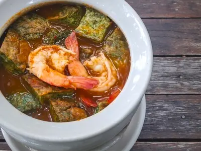 Thai food Cha om egg curry with shrimp in a white bowl on a woo
