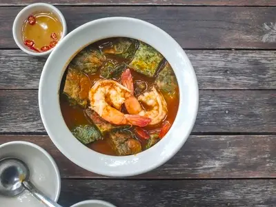 Thai food Cha om egg curry with shrimp in a white bowl on a woo