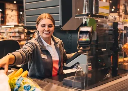 Young smiling woman working as a cashier in a grocery store  sitting at the counter