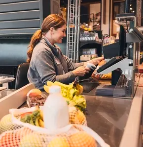 Young female working as a cashier in a grocery store scanning a bottle of juice