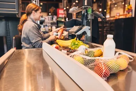 Products in a grocery store on the packaging board and a woman cashier