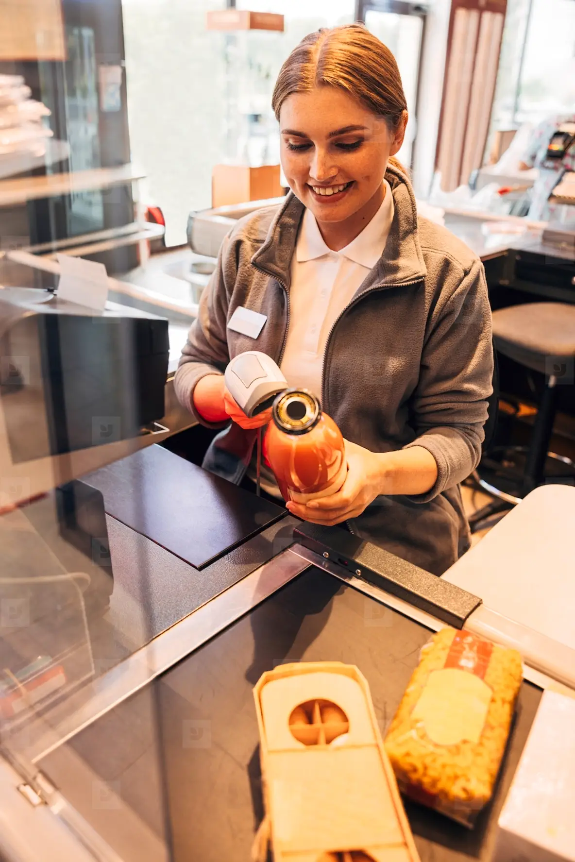 Smiling Female Cashier Holding A Bottle Of Juice And Using A Barcode ...