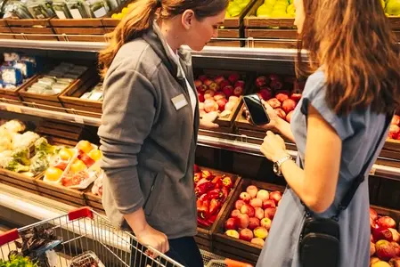 Female customer showing a supermarket employee a product that she is looking for Female customer showing a supermarket employee a product that she is looking for