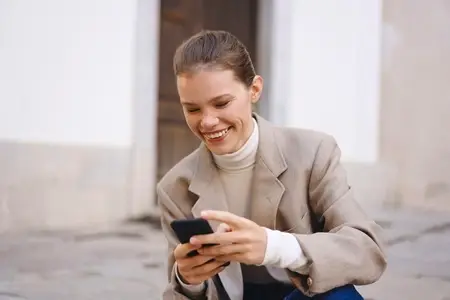 A Joyful Woman Engaged Enthusiastically with Her Smartphone While in an Urban Setting