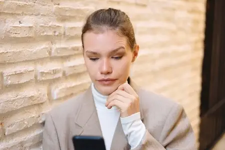 A young woman is deeply engaged with her smartphone while in an urban city setting