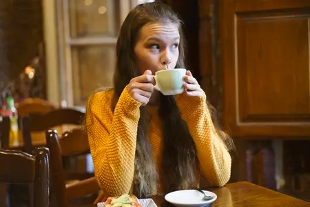 A young woman enjoys a warm drink in a cozy cafe  ideal for relaxing and socializing