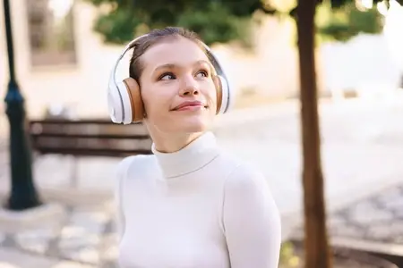 A young woman  carefree and charming  is enjoying music outdoors while wearing her headphones
